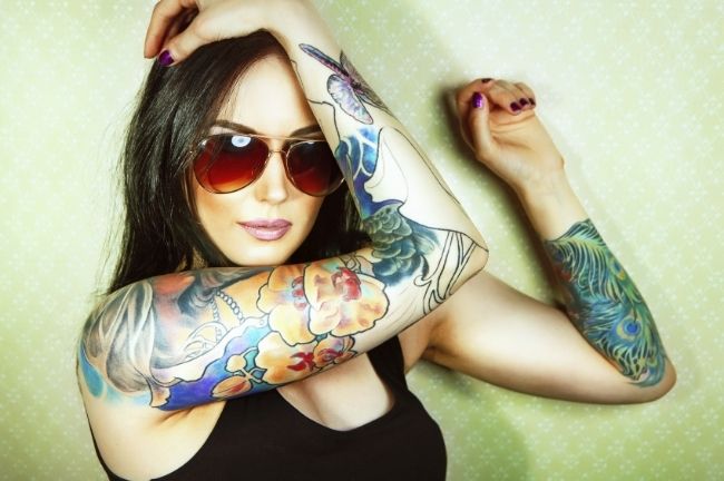 a young woman with brown hair and tattoo sleeves on her arms