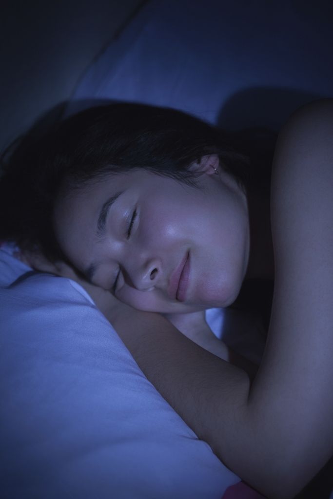  a young Asian woman sleeping on her right side in bed