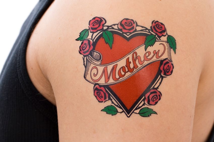 tattoo of a red heart and the text mum on the upper arm of a person